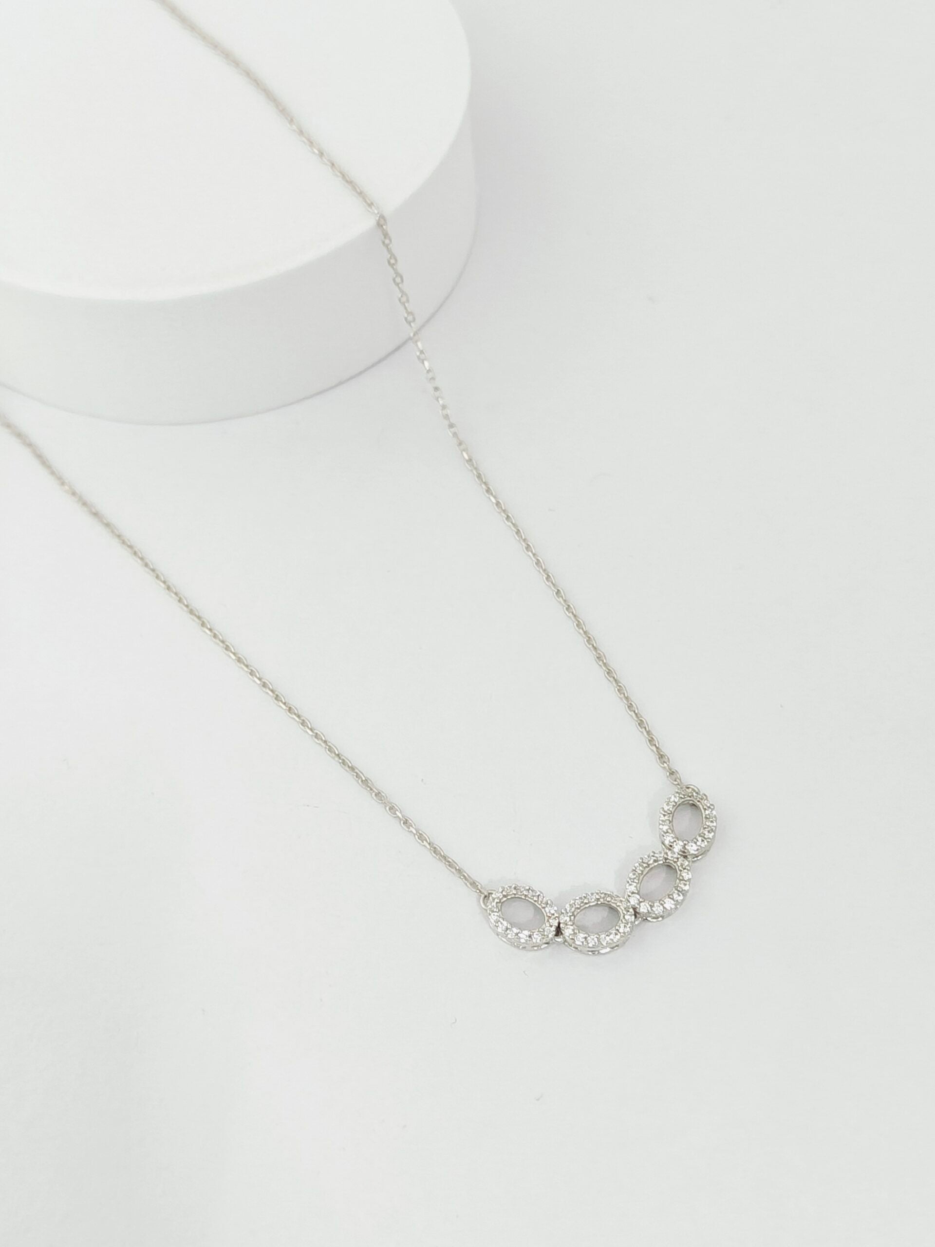 Silver necklace with circular pendants on a white background